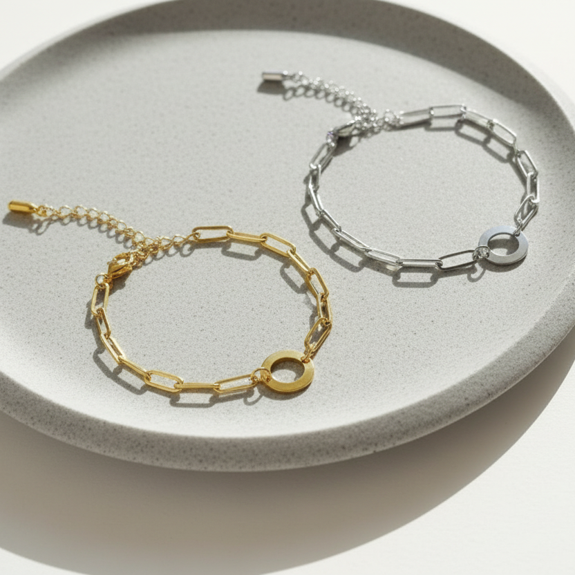 Two paperclip chain bracelets, one gold and one silver, displayed on a clean white background.