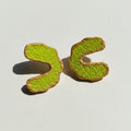 Two green and brown cookies shaped like question marks on a black and white geometric patterned background.