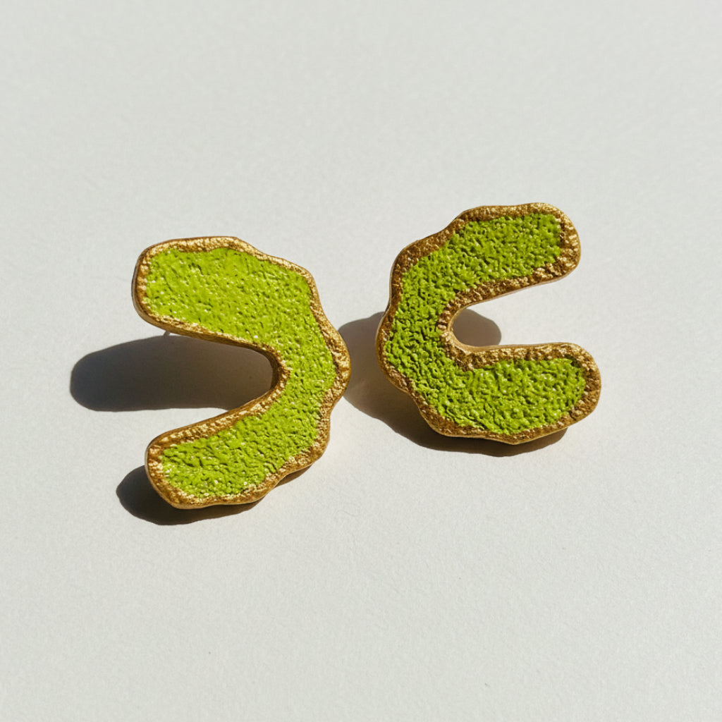 Two green and brown cookies shaped like question marks on a black and white geometric patterned background.
