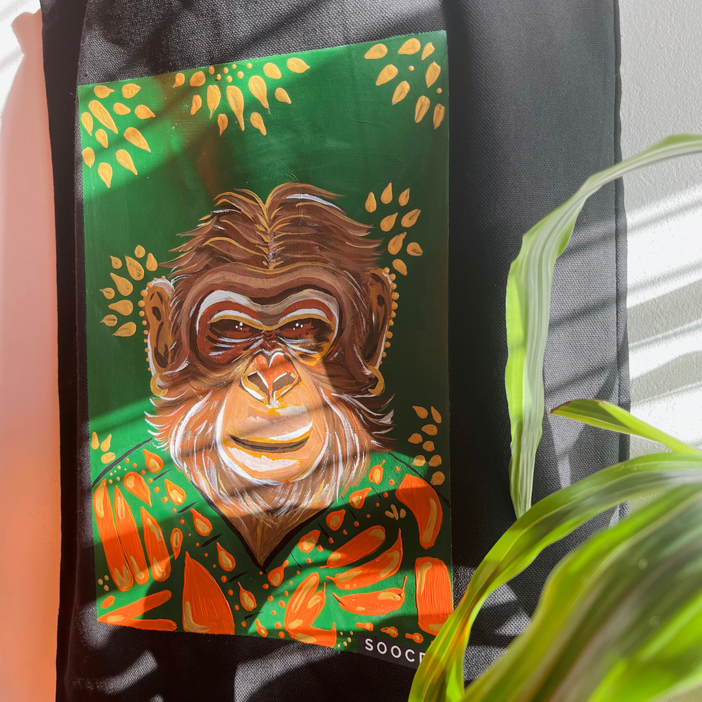 Decorative item with a monkey illustration on a green background, featuring leaves.